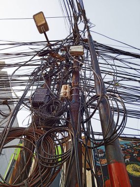 Jakarta, Endonezya. 17 Ekim 2023. Elektrik direklerindeki hileli elektrik kabloları. Karışık kablolar. Kablolar sarkıyor. Dağınık. Kötü kurulum. Tehlikelidir. Kirli. Elektrik şoku riski var. Yüksek voltaj.