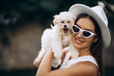 Güzel bir kadın küçük köpeğini tutuyor.