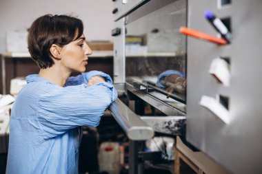 Matbaada çalışan kağıt ve boyalarla çalışan bir kadın.