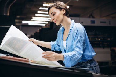 Matbaada çalışan kağıt ve boyalarla çalışan bir kadın.