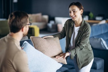 Mobilya dükkanında koltuk ve yastık seçen bir çift.