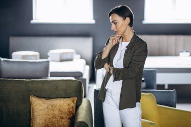 Mobilya dükkanında kanepe ve yastık seçen genç bir kadın.