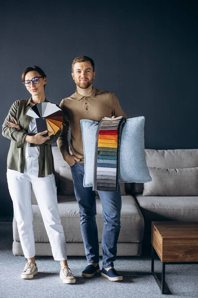 Woman and man designer with textile swatches and wooden palette at furniture store