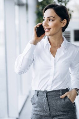 Vitrindeki telefonu kullanan bir iş kadını.