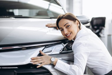 Güzel bir kadın arabaya sarılıyor.