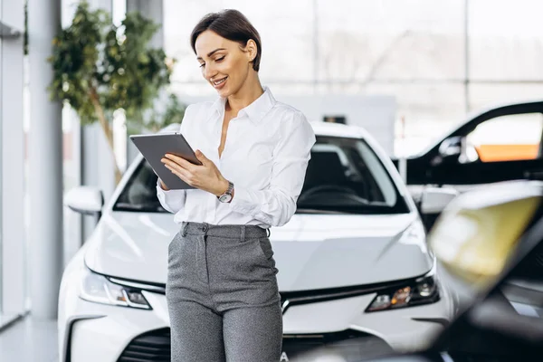 Young saleswoman with tablet in a car showroom