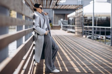 Sokakta yürüyen gri paltolu kadın portresi