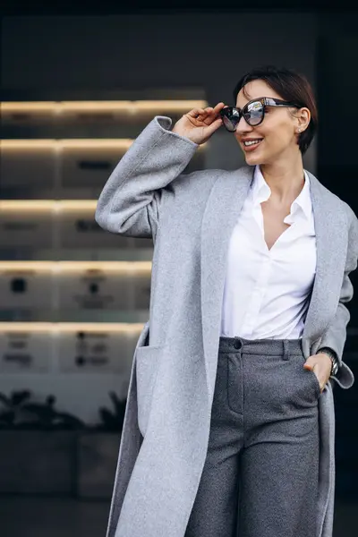 オフィスビル外の灰色のコートの美しいビジネス女性 — ストック写真