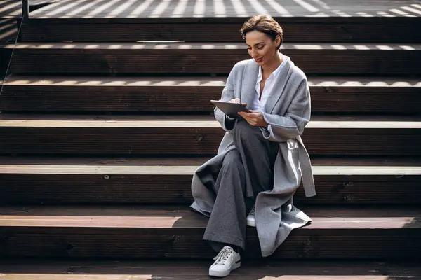 階段に座ってタブレットで作業するビジネス女性 — ストック写真