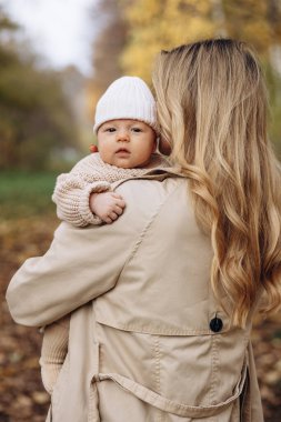 Anne yeni doğmuş çocuğunu kucağına alıp parkta yürüyor.