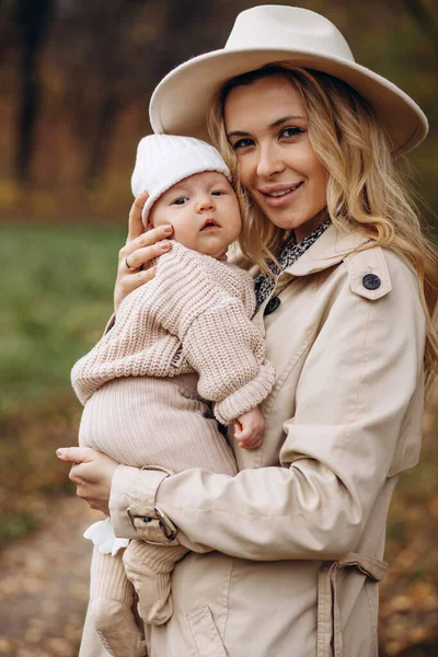 Anne yeni doğmuş çocuğunu kucağına alıp parkta yürüyor.