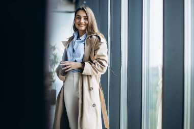 Ofis binasında elinde belgeler ve dosyalarla dolaşan bir iş kadını.