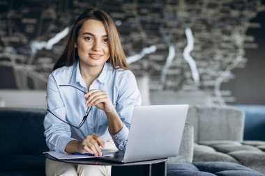 Serin ofis bölgesinde dizüstü bilgisayarda çalışan genç iş kadını.