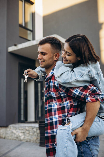 Young family holding keys from their new home