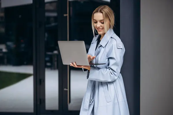 Młoda Kobieta Niebieskim Płaszczu Stojąca Przy Budynku Biurowym Laptopem — Zdjęcie stockowe