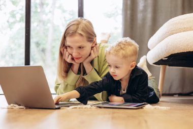 Oğlu tablet oyunlarında oynarken bilgisayar başında çalışan bir kadın