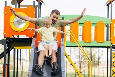 Baba oğul oyun parkında kayıyor.