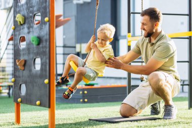 Baba oğul oyun alanında oynuyorlar.