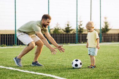 Baba oğul futbol sahasında oynuyorlar.