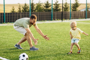 Baba oğul futbol sahasında oynuyorlar.