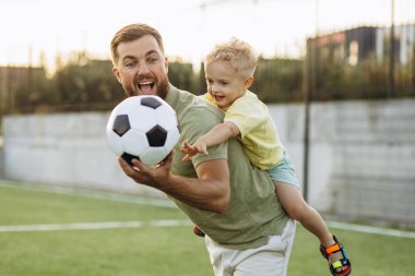 Baba oğul futbol sahasında oynuyorlar.