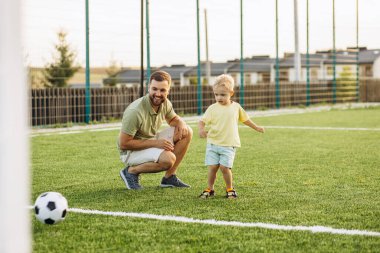 Baba oğul futbol sahasında oynuyorlar.