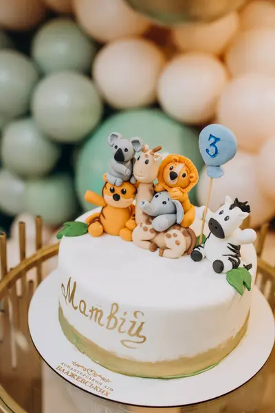 Birthday cake with animals decoration and balloons on the background