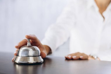 Otel lobisindeki iş kadını zili çalar, fotoğraf zilini ve elini kapatır.