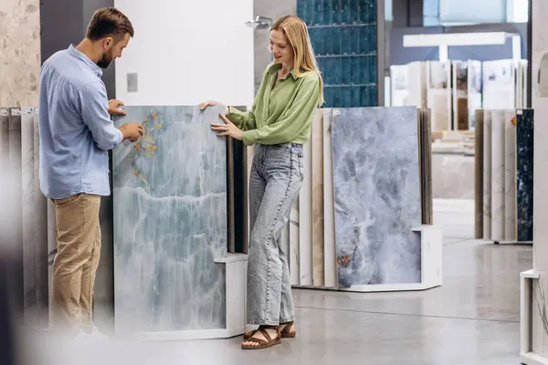 Young man with sales woman choosing tiles at building market