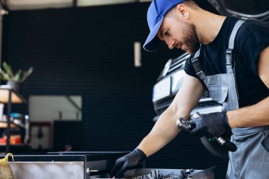 Araba servisinde ingiliz anahtarı ve diğer araçları kullanan oto tamircisi