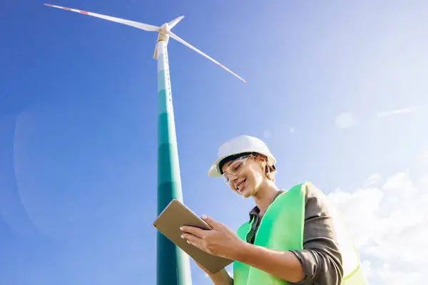 Woman working on tablet, controlling functioning of wind turbines