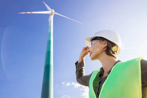 戴头盔站在风力涡轮机旁边的女工程师 — 图库照片