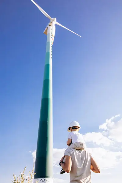 父亲和儿子一起坐在风车涡轮机旁 — 图库照片