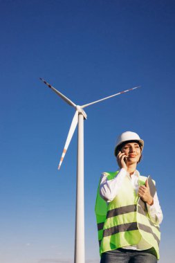 Yel değirmeni türbinlerinin yanında konuşan mimar kadın.