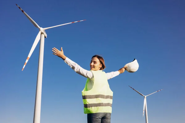 戴头盔站在风力涡轮机旁边的女工程师 — 图库照片