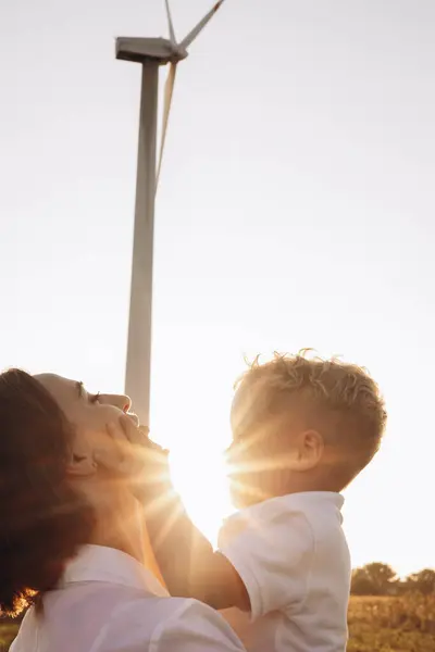 妈妈和儿子拥抱在风车涡轮机旁 — 图库照片