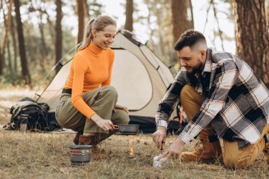 Ormanda birkaç gezgin suyu ısıtmak için gaz lambası kullanıyor.
