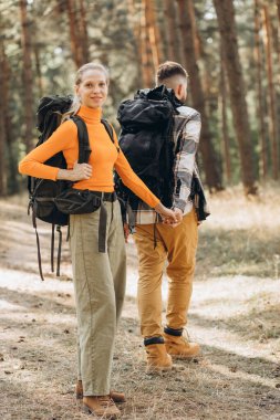 Çantalarla yürüyüş yapan ve ormanda yürüyen çiftler.