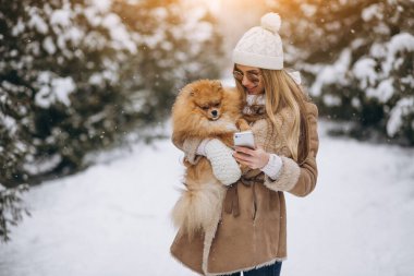 Kışın telefonu ve köpeği olan bir kadın.