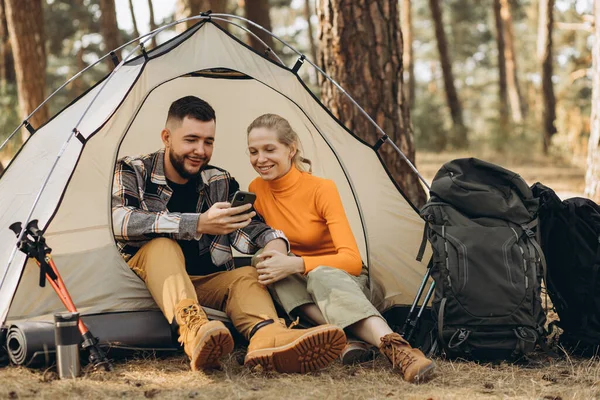 ラップトップで作業している森のテントに座っているカップル — ストック写真