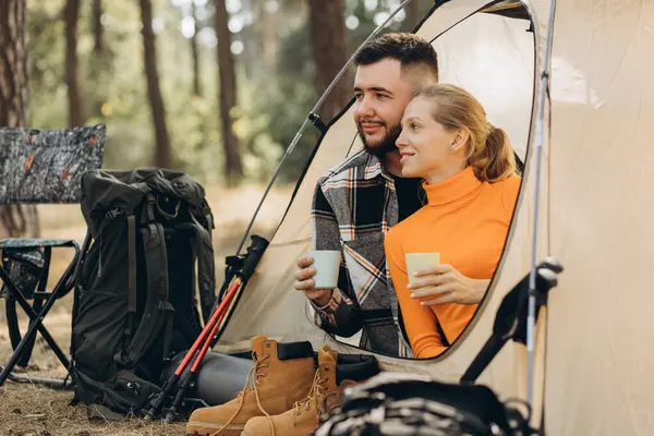 森で紅茶を飲むテントで一緒に座っている旅行者のカップル — ストック写真