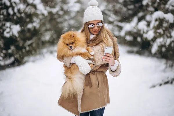 Woman with dog and phone in winter