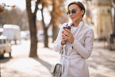 Palto giyen ve kahve içen bir kadın.