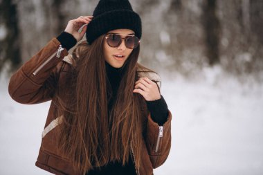 Kış parkında şapkalı ve rahat ceketli güzel bir kadın.