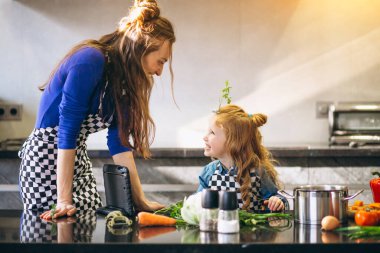 Anne ve kızı mutfakta tablet pişiriyorlar.
