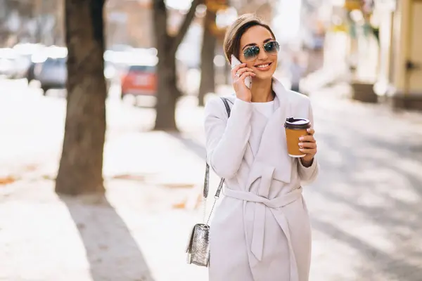 通りの外でコーヒーを飲んでいる電話を持つビジネス女性 — ストック写真