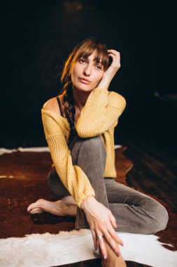 Yatak odasında sarı kazaklı genç bir kadın var.