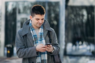 Genç yakışıklı gezgin dışarıda telefon kullanıyor.