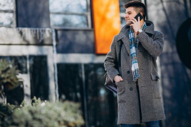 Genç yakışıklı gezgin dışarıda telefon kullanıyor.