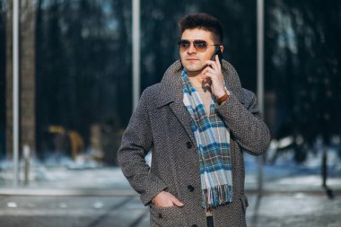 Genç yakışıklı adam dışarıda telefon kullanıyor.